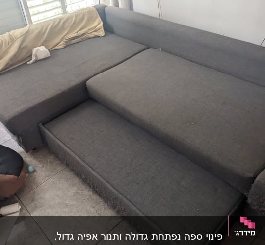ספה אפורה עם כריות וחפצים על הרצפה